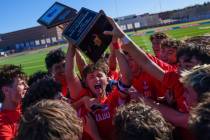 The Coronado boys soccer team, including Austin Kiernan with the trophy, celebrates during a 5A ...