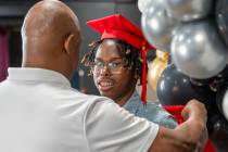 James Renfro helps his foster son, Isaiah Holliday, 18, out of his cap and gown after a photo d ...