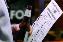 A man holds a betting sheet as he waits in line to bet on the NCAA basketball tournament at Wes ...